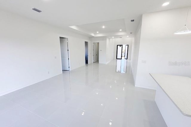 tiled spare room with a raised ceiling