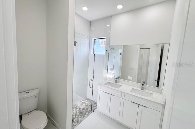 bathroom with tile patterned floors, vanity, toilet, and a shower with door