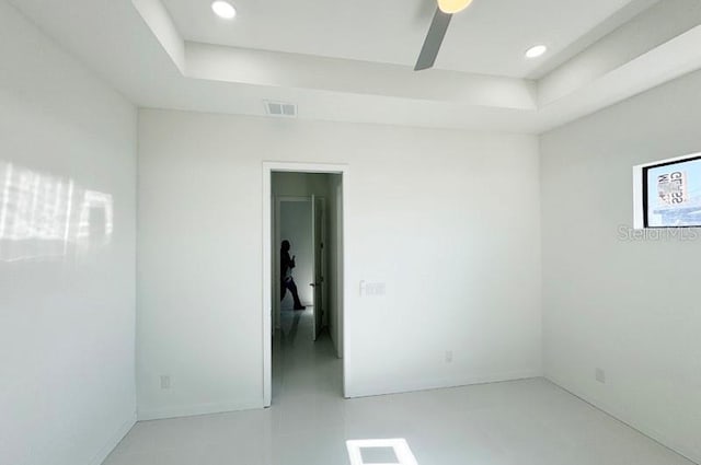 spare room with a raised ceiling and ceiling fan