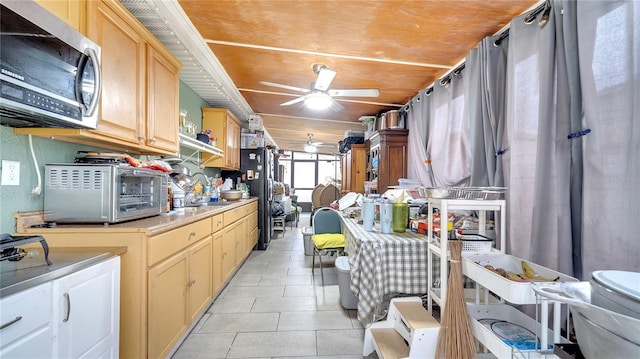 kitchen with light brown cabinets, ceiling fan, wood ceiling, light tile patterned flooring, and black fridge