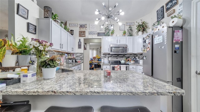 kitchen featuring stainless steel appliances, backsplash, a peninsula, and a breakfast bar area