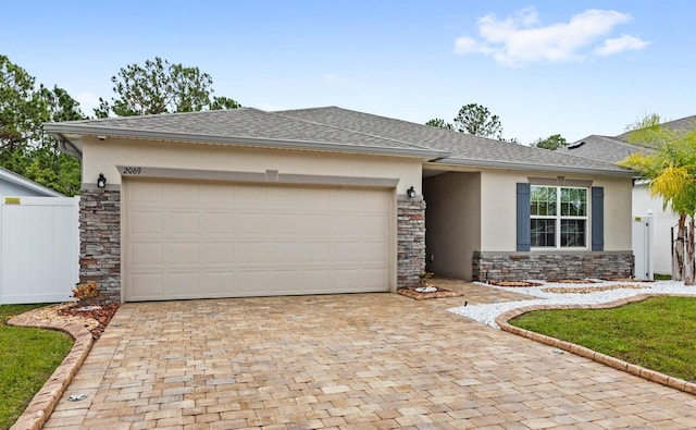 view of front of home featuring an attached garage, fence, stone siding, decorative driveway, and stucco siding