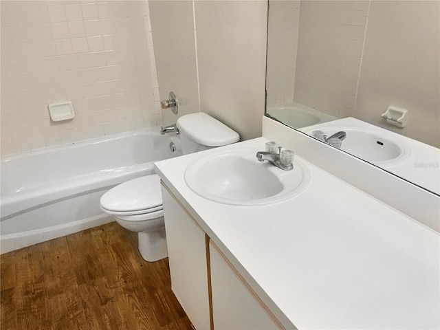 full bathroom featuring vanity, hardwood / wood-style flooring, toilet, and tiled shower / bath combo