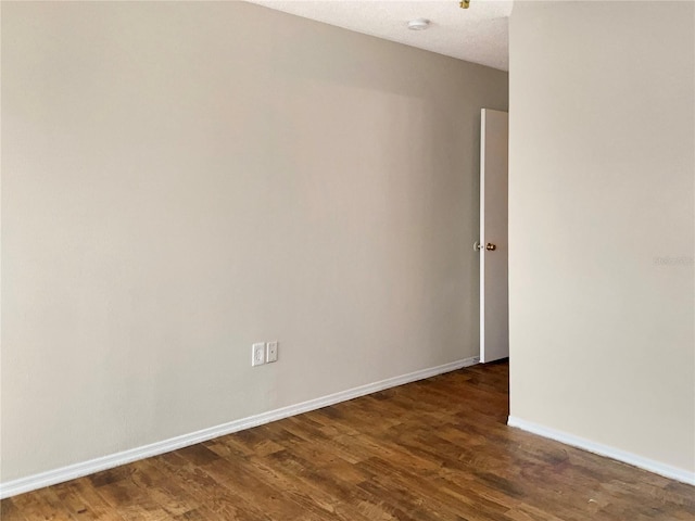 unfurnished room featuring a textured ceiling and dark hardwood / wood-style floors