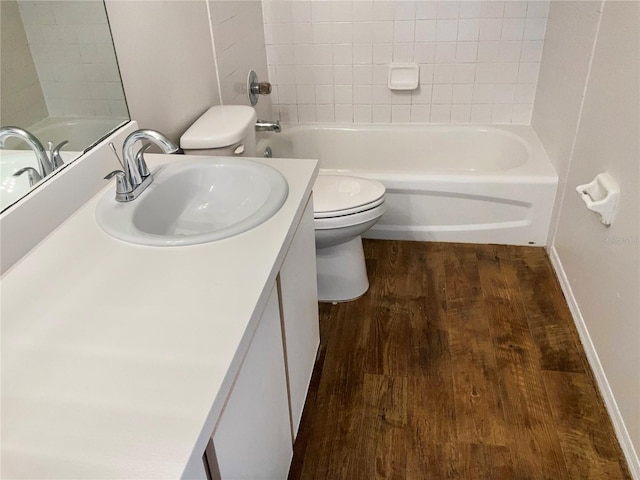 full bathroom with vanity, wood-type flooring, tiled shower / bath combo, and toilet