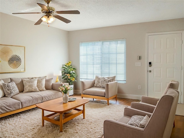 living room with ceiling fan, light wood-type flooring, and a textured ceiling