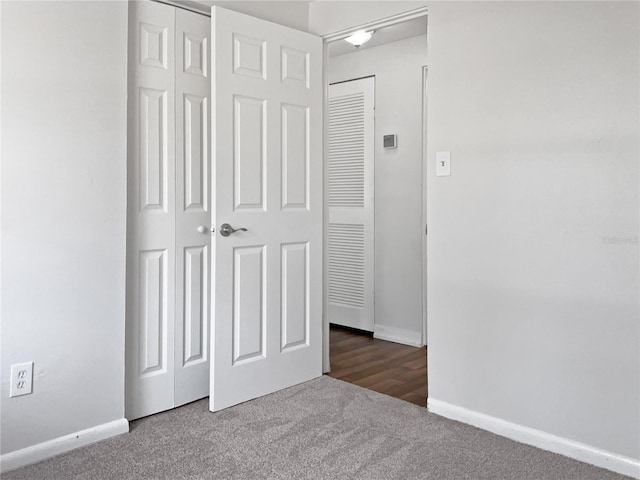 unfurnished bedroom with dark carpet and a closet