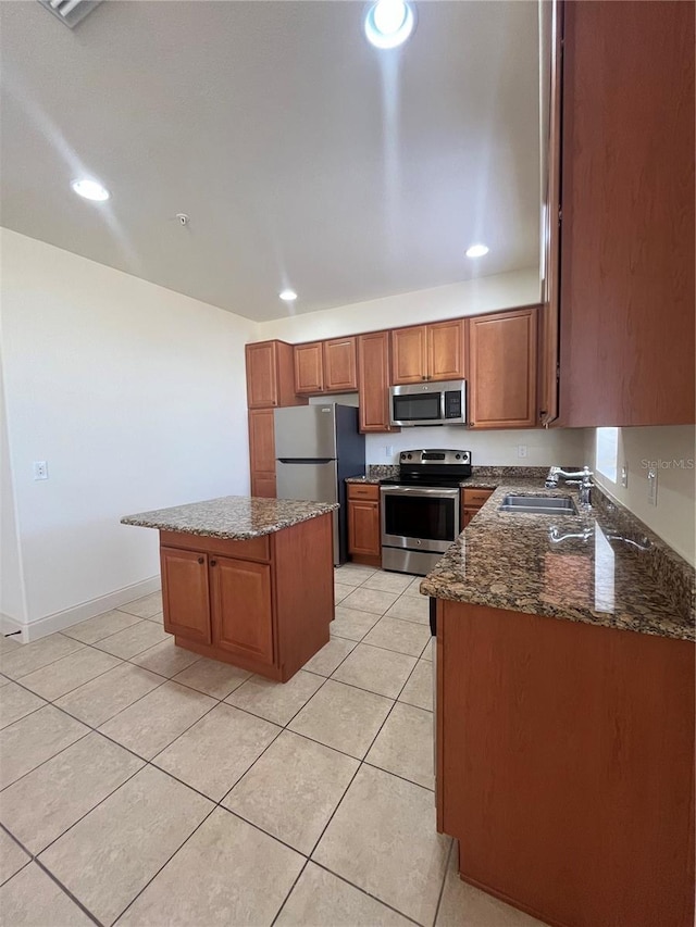 kitchen with a center island, sink, stainless steel appliances, dark stone countertops, and light tile patterned floors