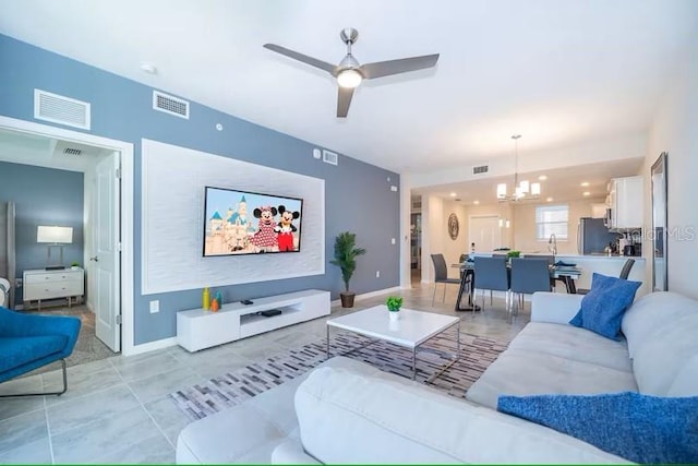 living room with light tile patterned floors and ceiling fan with notable chandelier