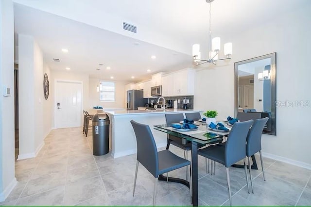 tiled dining room with sink and a notable chandelier