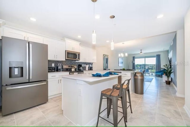 kitchen featuring kitchen peninsula, appliances with stainless steel finishes, white cabinets, and a breakfast bar area