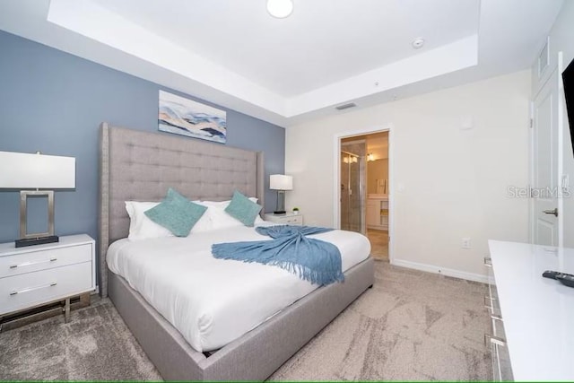 bedroom with a raised ceiling and light carpet