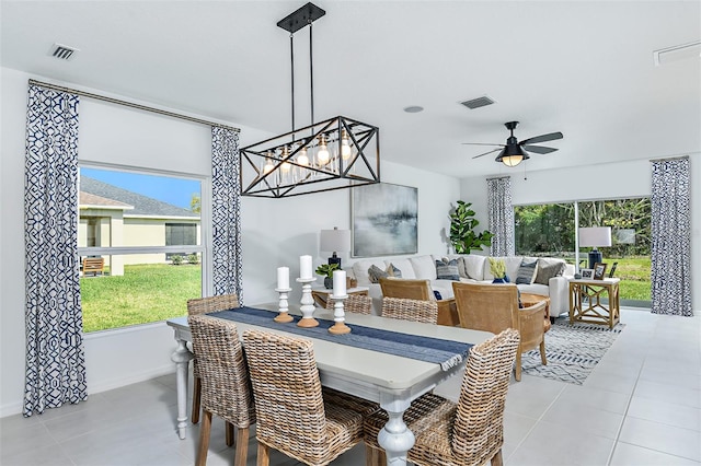 dining area featuring ceiling fan with notable chandelier, a healthy amount of sunlight, and light tile patterned flooring