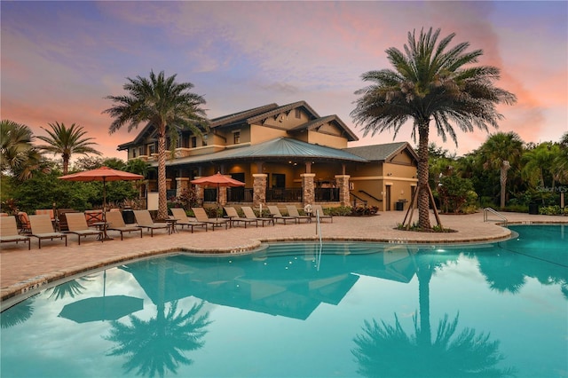 pool at dusk featuring a patio