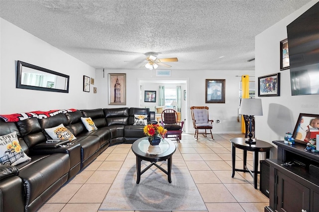 living room featuring ceiling fan, light tile patterned flooring, and a textured ceiling