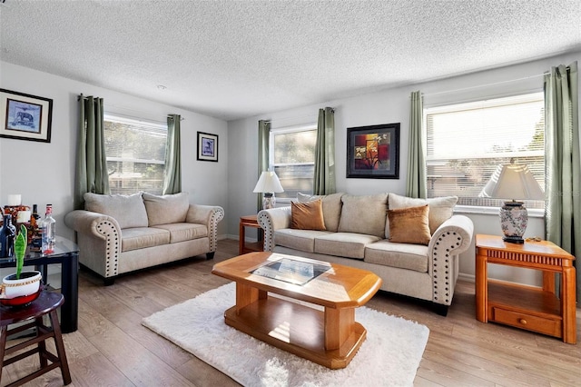 living room with light wood-type flooring, a textured ceiling, and a wealth of natural light