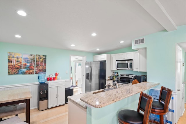 kitchen featuring light stone countertops, sink, kitchen peninsula, white cabinets, and appliances with stainless steel finishes