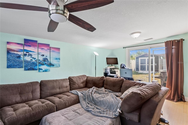 living room featuring ceiling fan, a textured ceiling, and hardwood / wood-style flooring