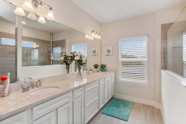 bathroom with vanity, tiled shower, and an inviting chandelier