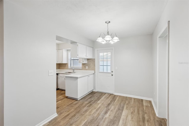 kitchen with sink, white cabinets, backsplash, a chandelier, and pendant lighting