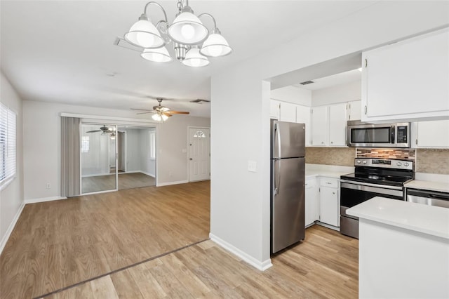 kitchen with stainless steel appliances, white cabinetry, light hardwood / wood-style floors, and hanging light fixtures