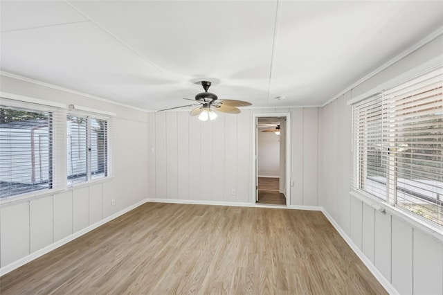 unfurnished room featuring ceiling fan, crown molding, light wood-type flooring, and a wealth of natural light