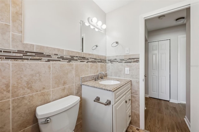 bathroom with tile walls, toilet, and vanity