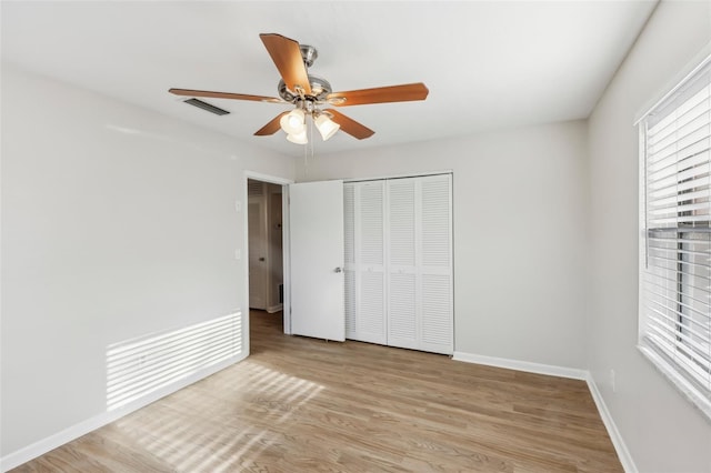 unfurnished bedroom featuring ceiling fan, light hardwood / wood-style floors, and a closet