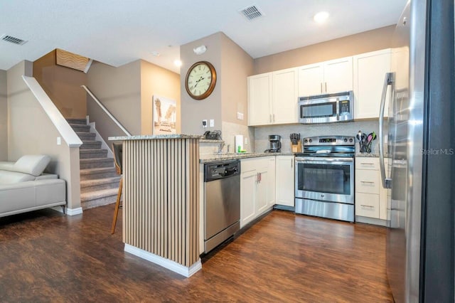 kitchen with kitchen peninsula, white cabinetry, stainless steel appliances, and light stone counters