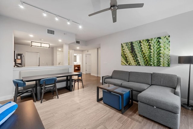 living room featuring ceiling fan, rail lighting, and light wood-type flooring