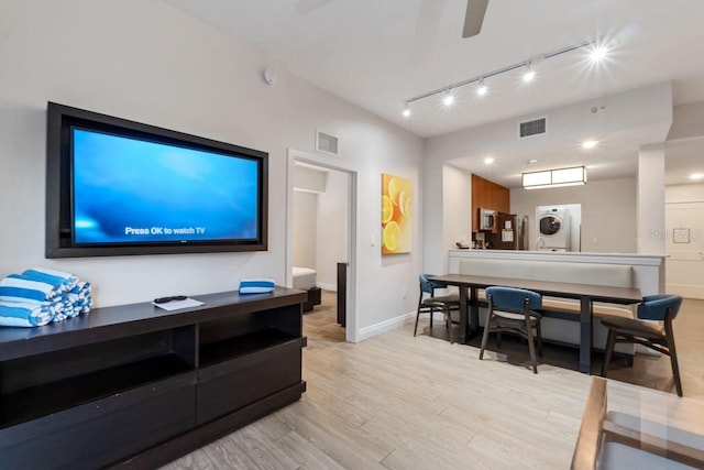 living room with light hardwood / wood-style floors, washer / dryer, and rail lighting