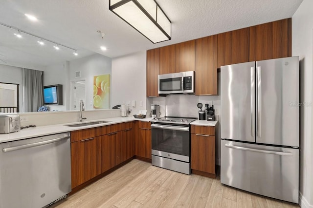 kitchen featuring a textured ceiling, stainless steel appliances, light hardwood / wood-style flooring, and sink