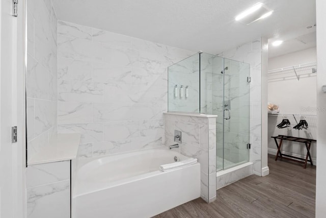 bathroom featuring a textured ceiling, wood-type flooring, and shower with separate bathtub