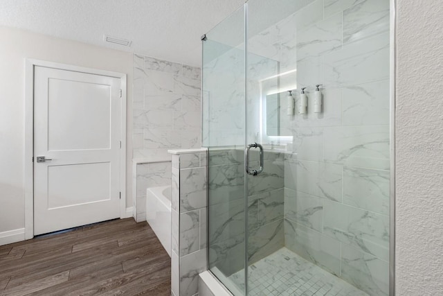 bathroom featuring hardwood / wood-style floors, independent shower and bath, and a textured ceiling