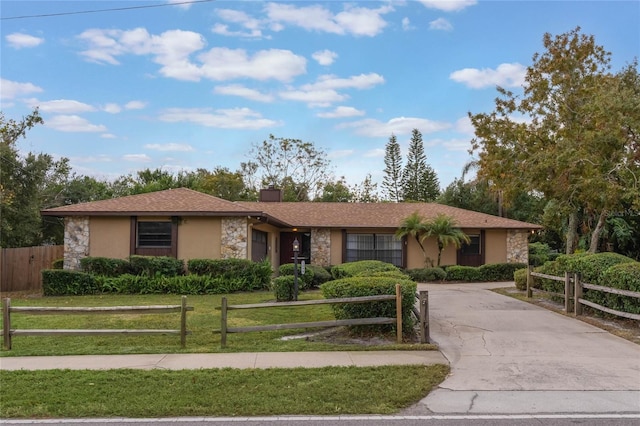 ranch-style home with a fenced front yard, stone siding, driveway, and stucco siding