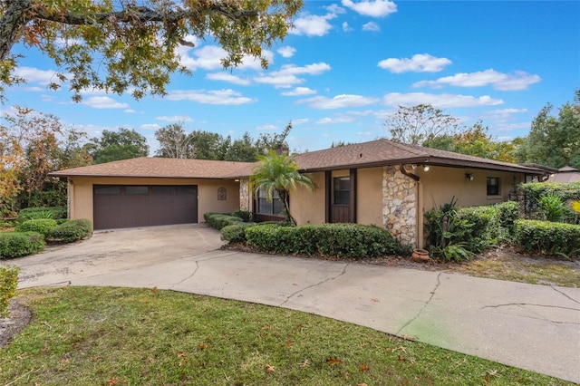 ranch-style house with stucco siding, stone siding, an attached garage, and driveway