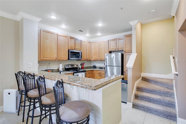 kitchen featuring light stone countertops, kitchen peninsula, a kitchen bar, light tile patterned flooring, and appliances with stainless steel finishes