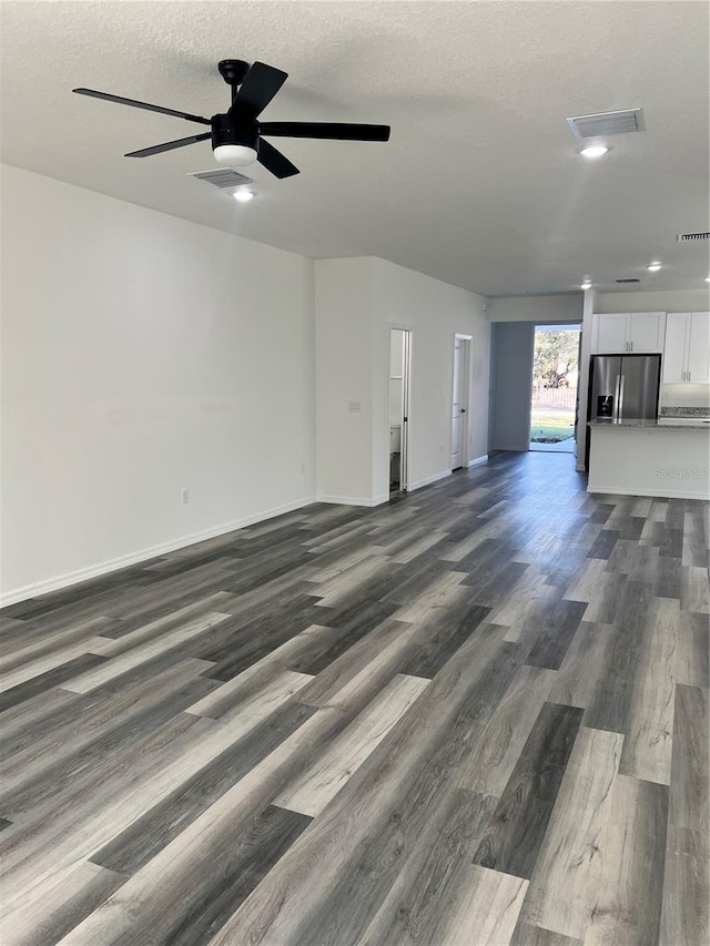 unfurnished living room with a textured ceiling, dark hardwood / wood-style floors, and ceiling fan