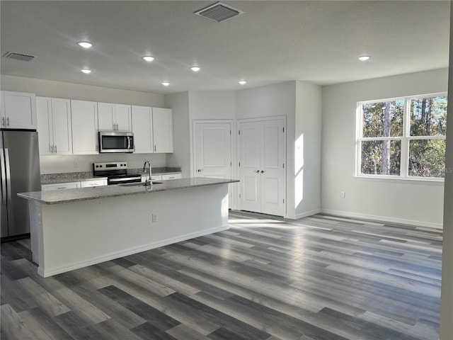 kitchen with light stone countertops, a center island with sink, and stainless steel appliances