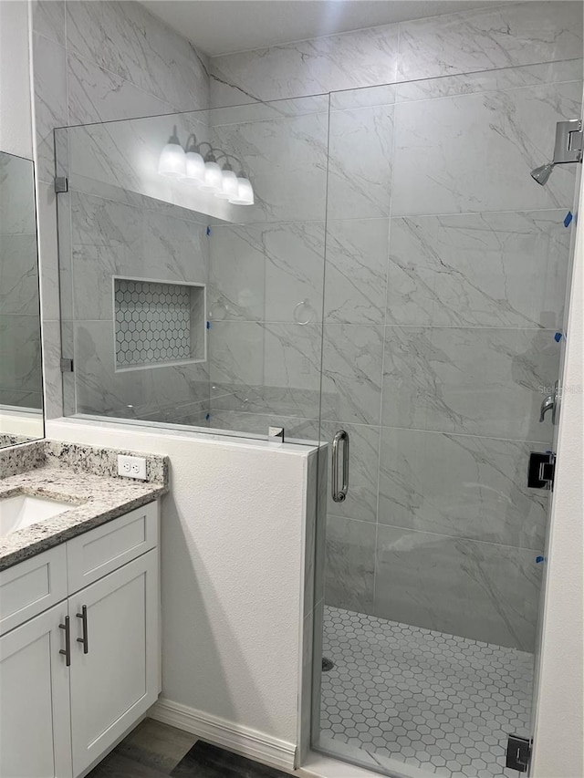 bathroom featuring a shower with door and vanity