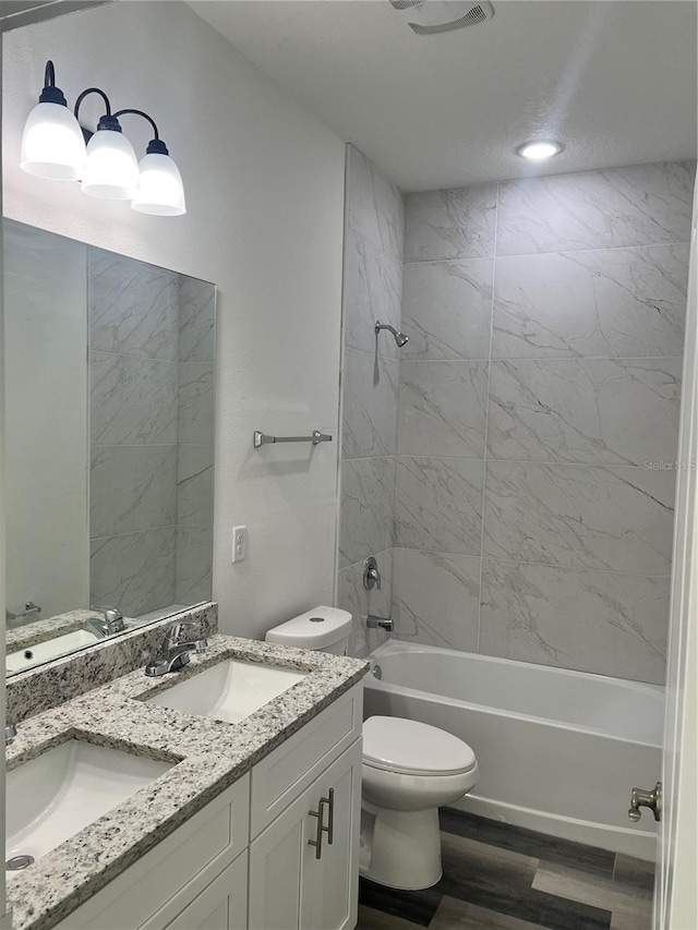 full bathroom featuring toilet, vanity, tiled shower / bath combo, and hardwood / wood-style flooring