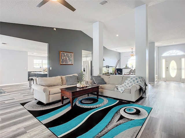 living room featuring a textured ceiling, light hardwood / wood-style flooring, ceiling fan, and lofted ceiling