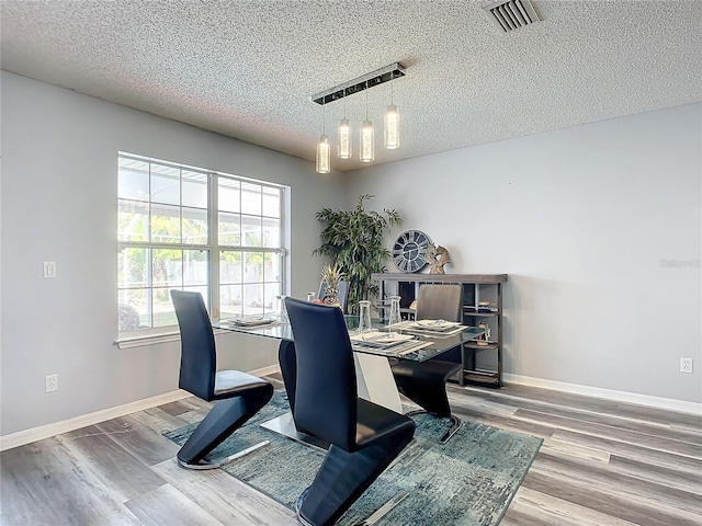 dining area with a chandelier, wood-type flooring, and a textured ceiling