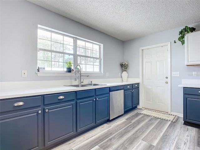 kitchen with sink, stainless steel dishwasher, blue cabinets, a textured ceiling, and light wood-type flooring