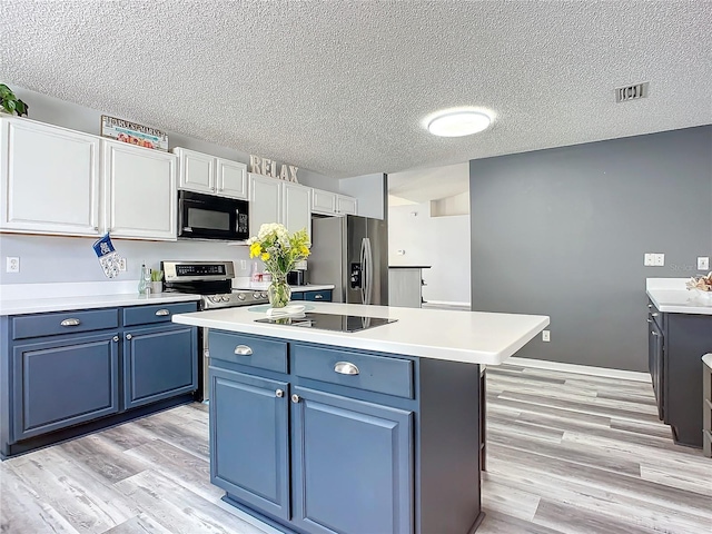 kitchen with light wood-type flooring, a textured ceiling, blue cabinets, black appliances, and white cabinetry