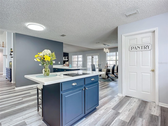 kitchen featuring a kitchen island, a kitchen bar, light hardwood / wood-style floors, and a textured ceiling