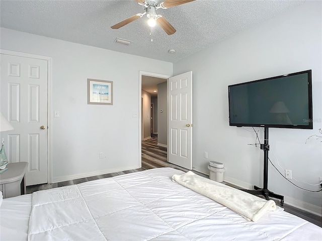 bedroom featuring a textured ceiling, dark hardwood / wood-style floors, and ceiling fan