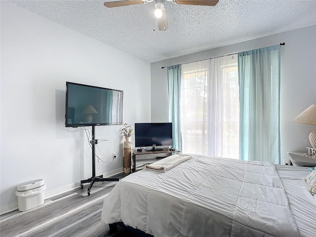 bedroom with hardwood / wood-style floors, a textured ceiling, and ceiling fan