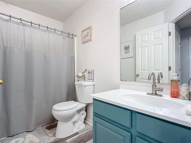 bathroom featuring hardwood / wood-style flooring, vanity, toilet, and a textured ceiling