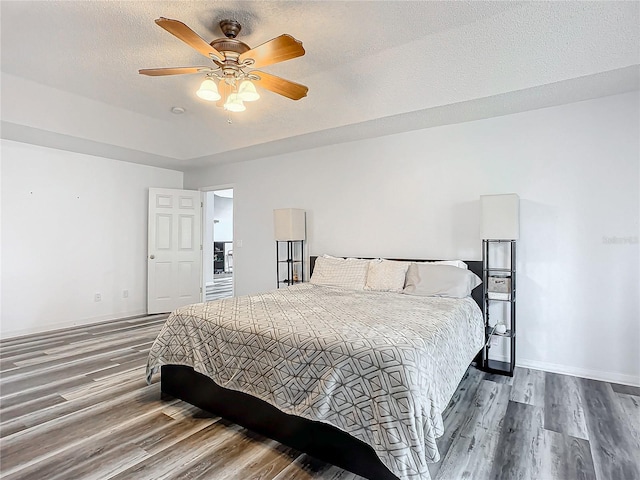 bedroom with hardwood / wood-style floors, a textured ceiling, and ceiling fan